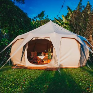 Spacious glamping tent set in a vibrant garden in São Paulo, Brazil, offering a luxurious camping experience surrounded by nature.